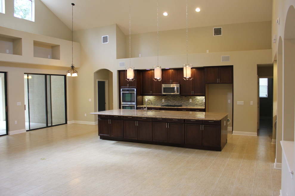 Inspiration for a large traditional l-shaped open plan kitchen in Tampa with an undermount sink, raised-panel cabinets, dark wood cabinets, granite benchtops, beige splashback, stainless steel appliances and ceramic floors.