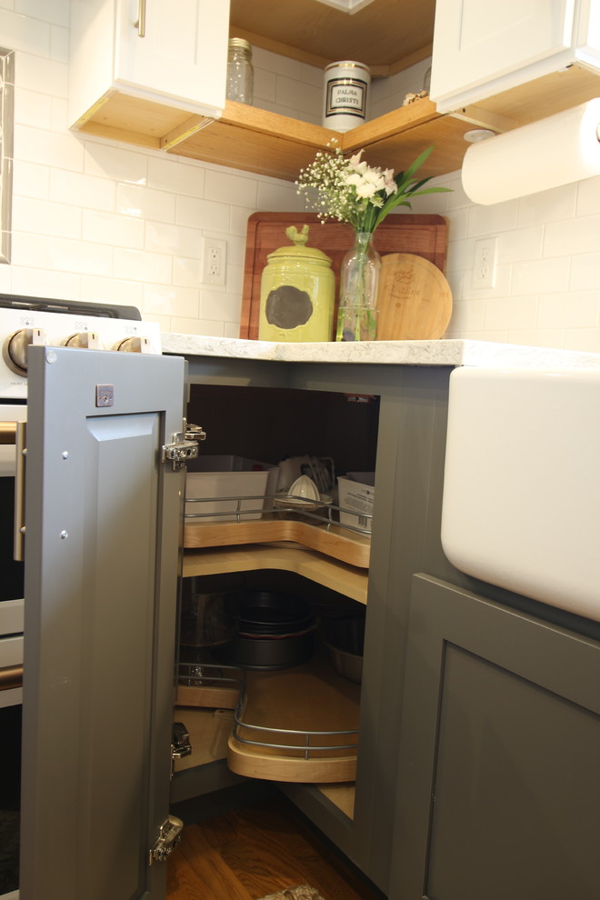 Enclosed kitchen - mid-sized transitional u-shaped medium tone wood floor and brown floor enclosed kitchen idea with a farmhouse sink, shaker cabinets, white cabinets, quartz countertops, white backsplash, subway tile backsplash, white appliances, no island and beige countertops