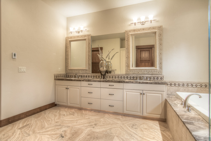 Mid-sized mountain style master beige tile bathroom photo with white cabinets, white walls, an undermount sink, tile countertops and recessed-panel cabinets