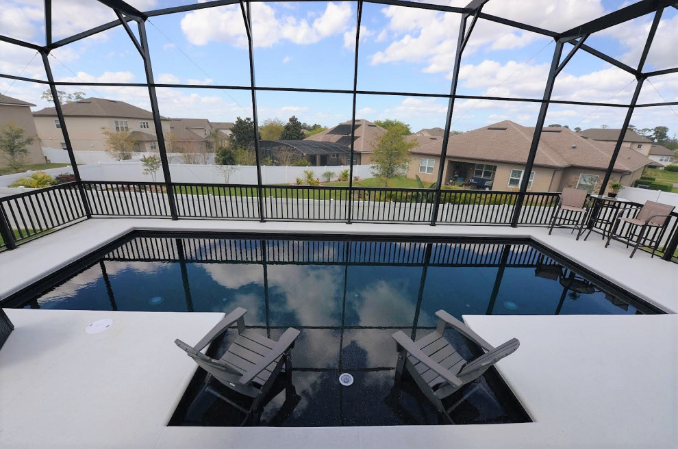 Ejemplo de piscina clásica de tamaño medio rectangular en patio trasero con losas de hormigón