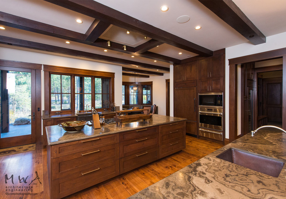 Huge transitional l-shaped dark wood floor open concept kitchen photo with a farmhouse sink, shaker cabinets, dark wood cabinets, paneled appliances, two islands and gray countertops