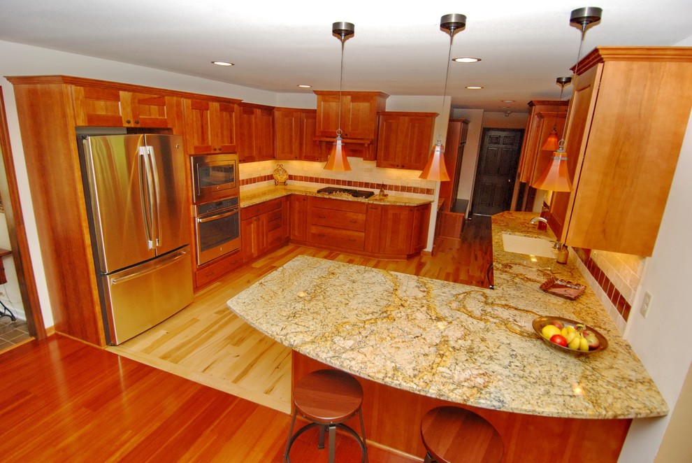 Inspiration for a mid-sized transitional u-shaped light wood floor eat-in kitchen remodel in Milwaukee with an undermount sink, flat-panel cabinets, medium tone wood cabinets, granite countertops, beige backsplash, stone tile backsplash, stainless steel appliances and no island