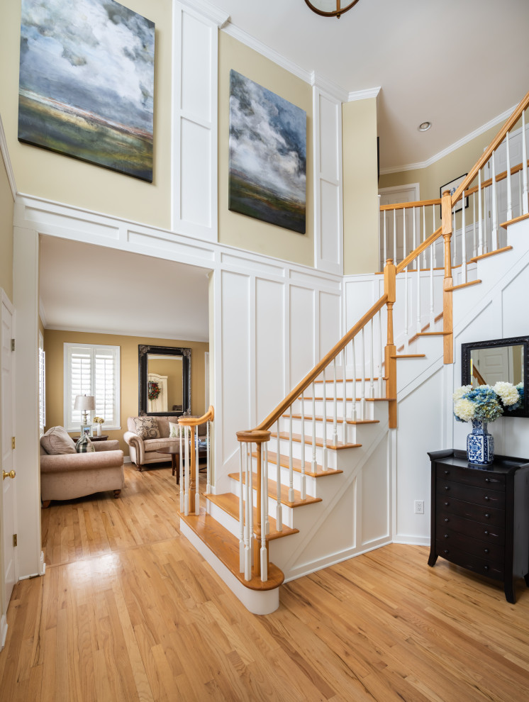 Photo of a medium sized foyer in Other with white walls, light hardwood flooring, a vaulted ceiling and panelled walls.