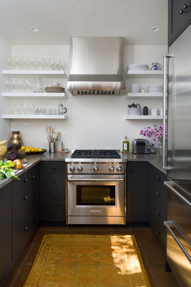 Inspiration for a small mediterranean galley eat-in kitchen in Santa Barbara with an undermount sink, flat-panel cabinets, black cabinets, white splashback, stainless steel appliances, terra-cotta floors and no island.