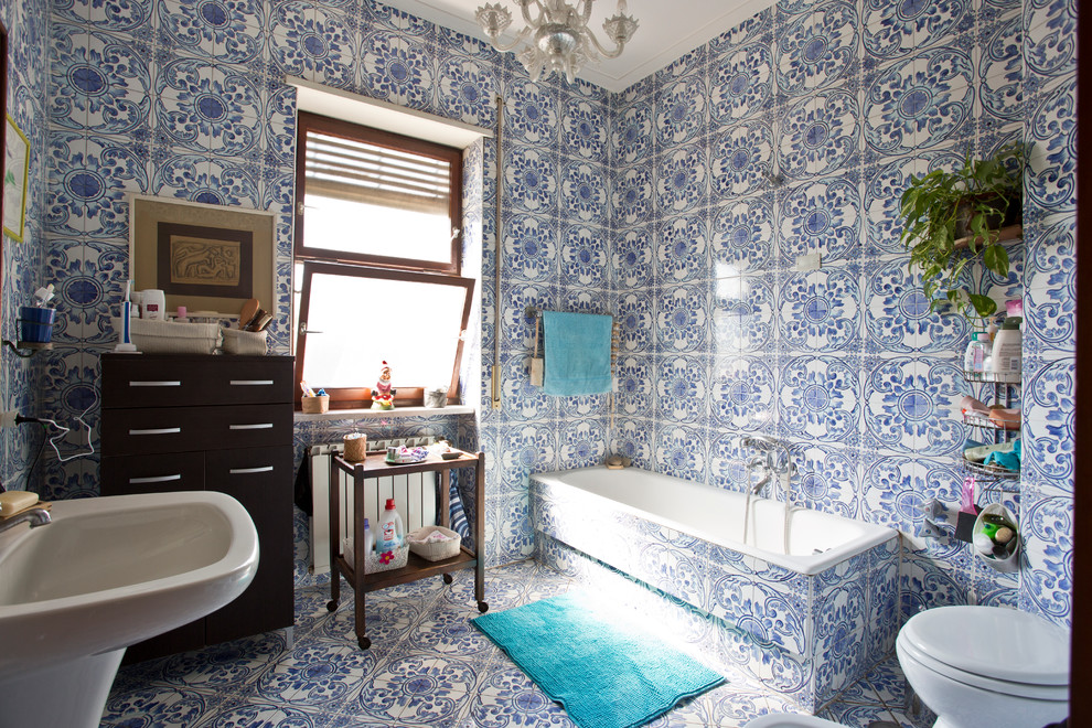 Photo of a large mediterranean master bathroom in Naples with furniture-like cabinets, dark wood cabinets, a drop-in tub, blue tile, ceramic tile, ceramic floors and a pedestal sink.