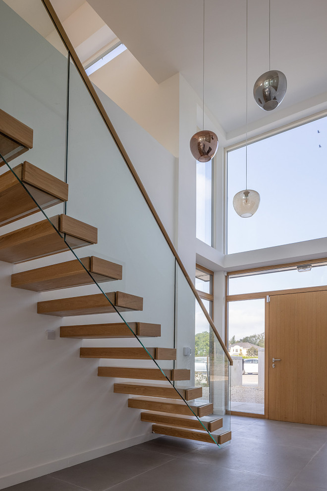 Идея дизайна: деревянная лестница на больцах, среднего размера в современном стиле с деревянными ступенями и стеклянными перилами