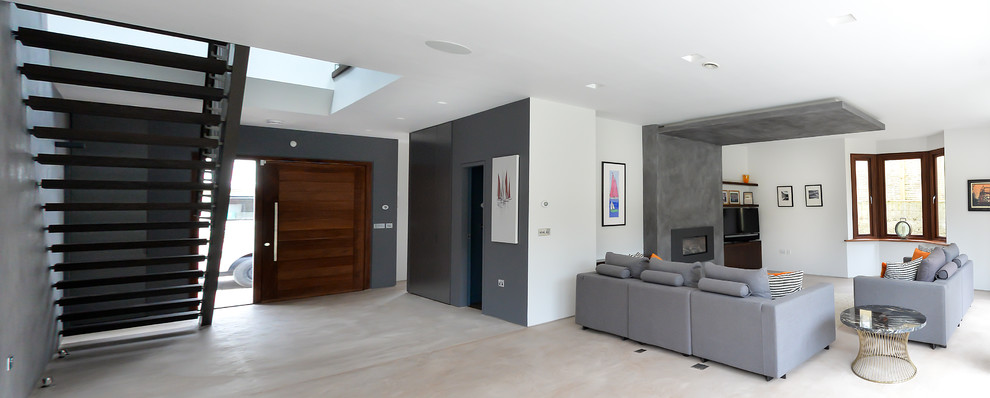 Inspiration for a large contemporary open concept living room in Sussex with grey walls, concrete floors, a standard fireplace, a plaster fireplace surround and a built-in media wall.
