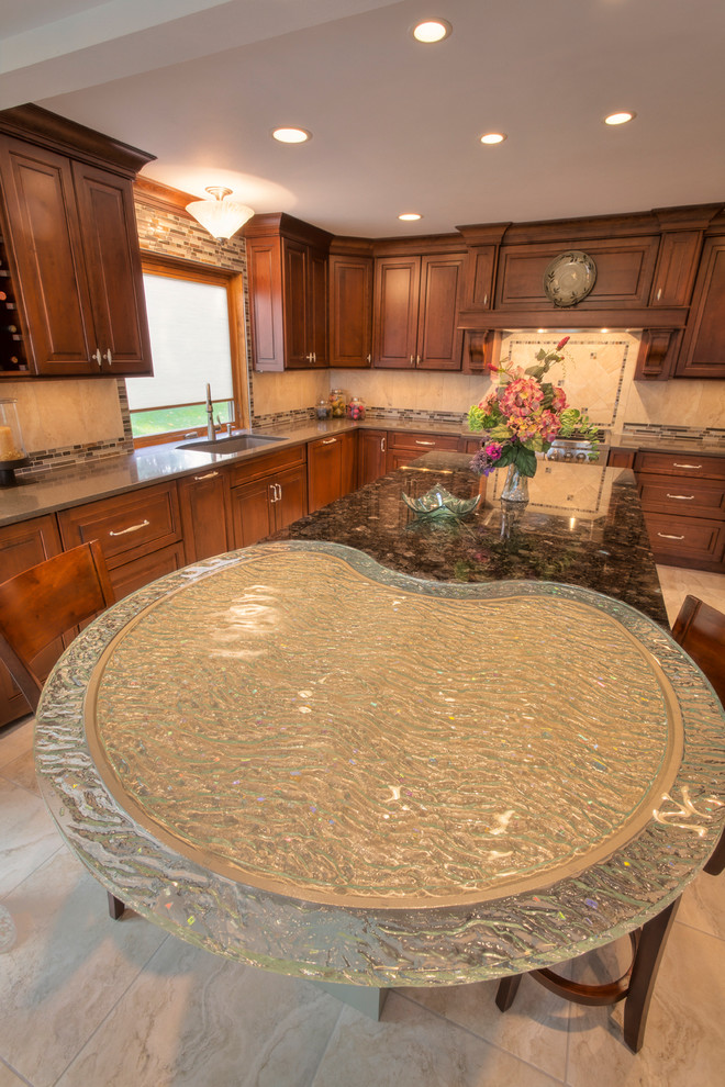 Example of a large transitional l-shaped ceramic tile eat-in kitchen design with an undermount sink, raised-panel cabinets, medium tone wood cabinets, glass countertops, multicolored backsplash, mosaic tile backsplash, paneled appliances and an island