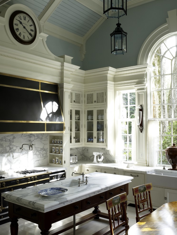 Photo of a traditional eat-in kitchen in New York with a farmhouse sink, black appliances, glass-front cabinets, white cabinets, marble benchtops, white splashback and marble splashback.