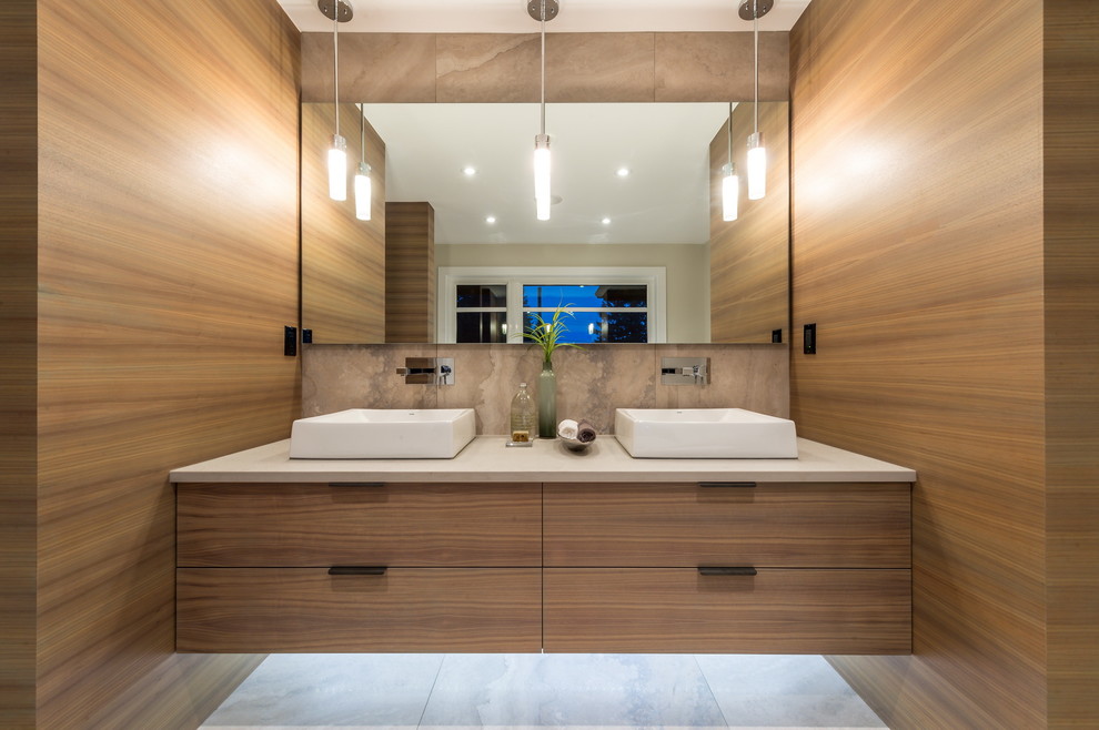 Inspiration for a large contemporary master bathroom in Vancouver with flat-panel cabinets, light wood cabinets, a freestanding tub, beige tile, stone tile, marble floors, a vessel sink and solid surface benchtops.