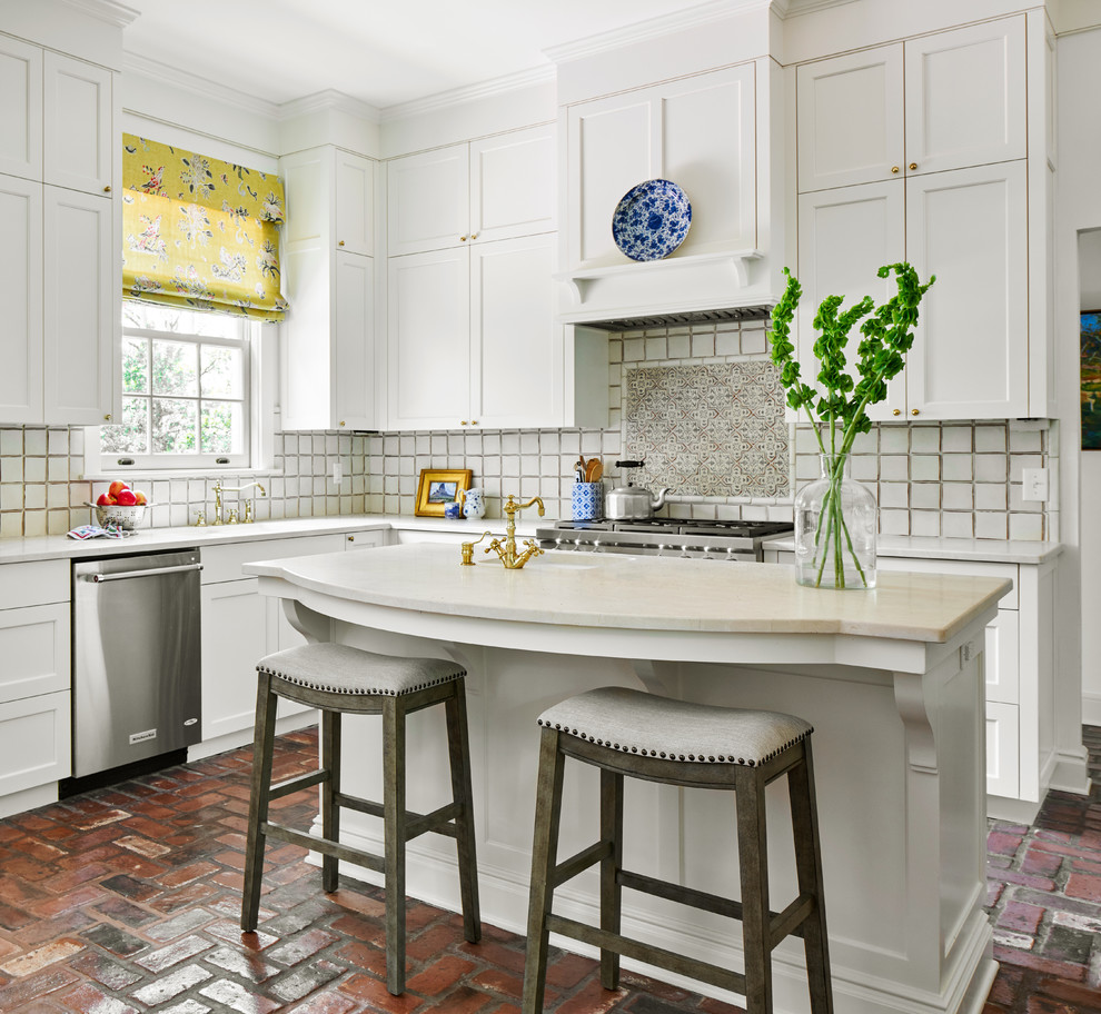 Inspiration for a mid-sized beach style l-shaped kitchen in Austin with an undermount sink, shaker cabinets, white cabinets, marble benchtops, white splashback, ceramic splashback, stainless steel appliances, brick floors, with island and white benchtop.