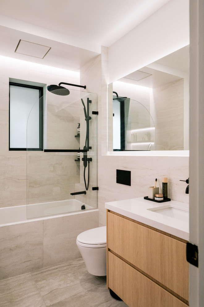 Foto på ett stort skandinaviskt vit badrum med dusch, med luckor med infälld panel, skåp i ljust trä, ett badkar i en alkov, en dusch/badkar-kombination, en vägghängd toalettstol, grå kakel, keramikplattor, vita väggar, klinkergolv i keramik, ett undermonterad handfat, bänkskiva i kvarts, grått golv och dusch med gångjärnsdörr