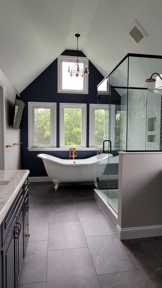 Photo of a large traditional master bathroom in Other with raised-panel cabinets, blue cabinets, a claw-foot tub, an open shower, a two-piece toilet, white tile, porcelain tile, blue walls, vinyl floors, an undermount sink, engineered quartz benchtops, grey floor, a hinged shower door, white benchtops, a niche, a double vanity, a built-in vanity and vaulted.