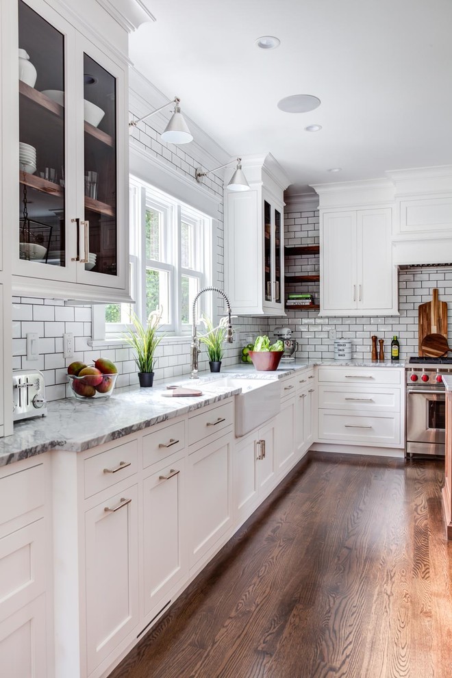 Inspiration for a mid-sized traditional u-shaped eat-in kitchen in Other with a farmhouse sink, recessed-panel cabinets, white cabinets, marble benchtops, white splashback, subway tile splashback, stainless steel appliances, multiple islands and brown floor.