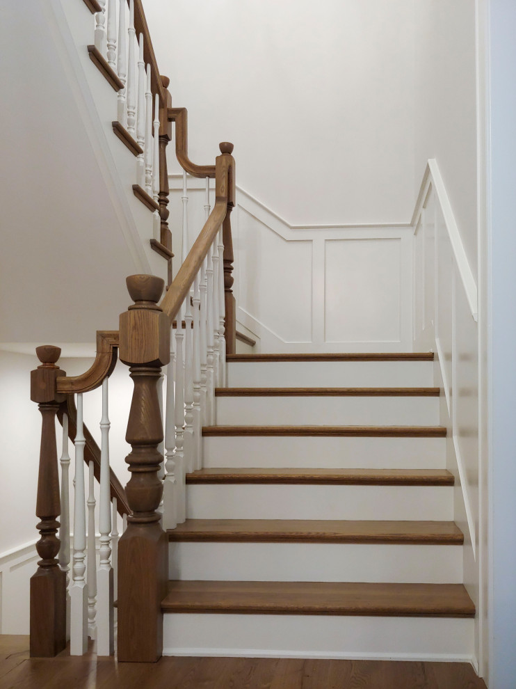 This is an example of a medium sized traditional wood u-shaped wood railing staircase in DC Metro with painted wood risers and wainscoting.