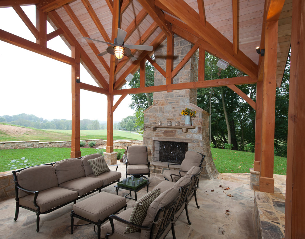 Photo of a large country backyard verandah in Baltimore with with fireplace, natural stone pavers and a roof extension.