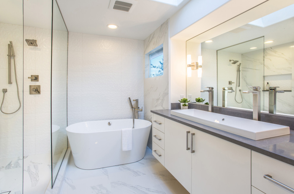 Photo of a mid-sized contemporary master bathroom in Seattle with flat-panel cabinets, white cabinets, a freestanding tub, a corner shower, white tile, porcelain tile, white walls, porcelain floors, a trough sink, engineered quartz benchtops, white floor, a hinged shower door, grey benchtops, a niche, a double vanity and a floating vanity.