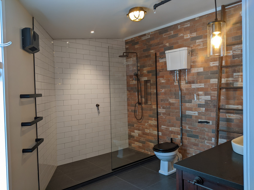 Bild på ett mellanstort industriellt svart svart en-suite badrum, med skåp i shakerstil, bruna skåp, en öppen dusch, en toalettstol med separat cisternkåpa, brun kakel, keramikplattor, vita väggar, klinkergolv i keramik, ett fristående handfat, träbänkskiva, grått golv och med dusch som är öppen
