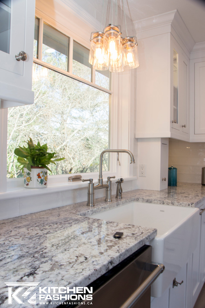 Large transitional u-shaped light wood floor home design photo with a farmhouse sink, shaker cabinets, white cabinets, granite countertops, white backsplash, subway tile backsplash, stainless steel appliances and no island