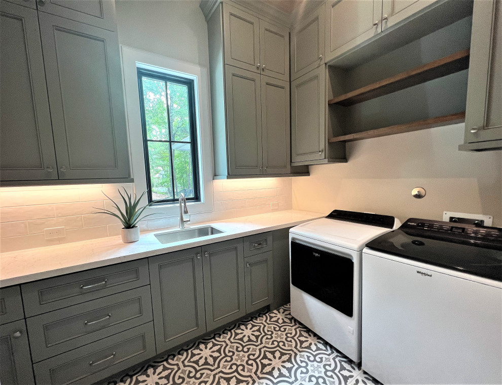 Photo of a mid-sized transitional u-shaped utility room in Houston with shaker cabinets, green cabinets, quartz benchtops, white splashback, subway tile splashback, beige walls, porcelain floors, a side-by-side washer and dryer, multi-coloured floor and white benchtop.