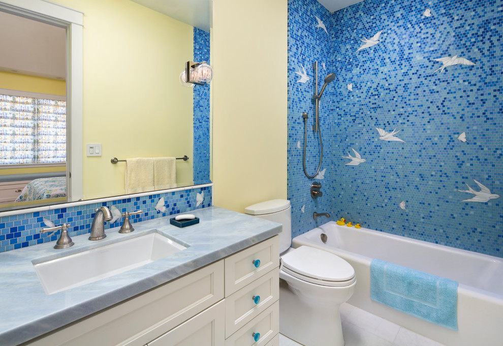 Photo of a mid-sized contemporary kids bathroom in San Diego with an undermount sink, recessed-panel cabinets, white cabinets, marble benchtops, an alcove tub, a one-piece toilet, blue tile, yellow walls, marble floors and glass tile.