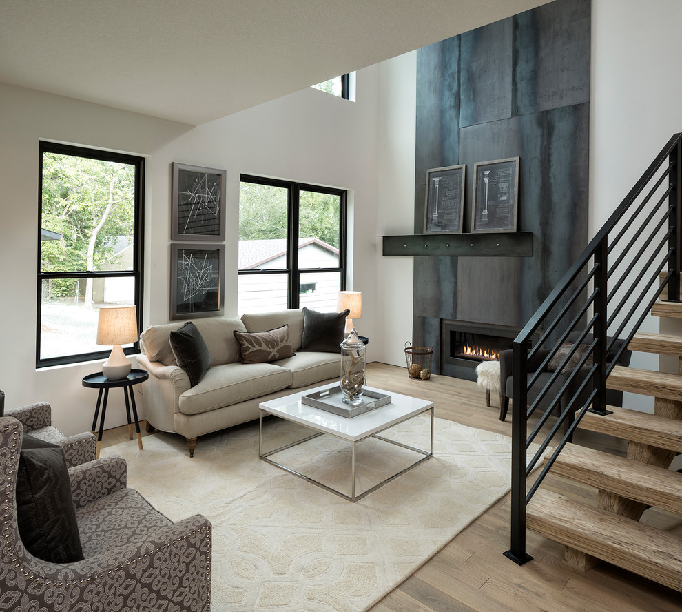 Photo of a mid-sized industrial open concept family room in Minneapolis with white walls, light hardwood floors, a ribbon fireplace, a metal fireplace surround, no tv and beige floor.