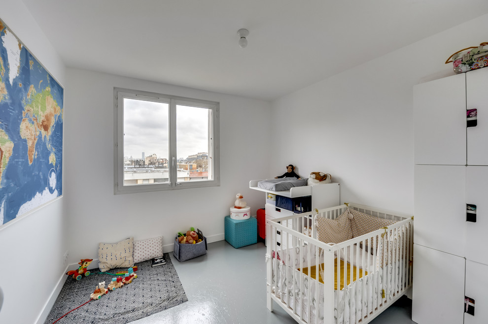 This is an example of a mid-sized midcentury gender-neutral nursery in Paris with white walls and painted wood floors.