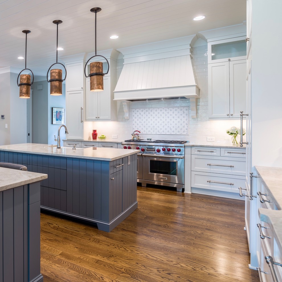 Large transitional l-shaped medium tone wood floor eat-in kitchen photo in Atlanta with a farmhouse sink, shaker cabinets, white cabinets, quartzite countertops, white backsplash, white appliances and two islands