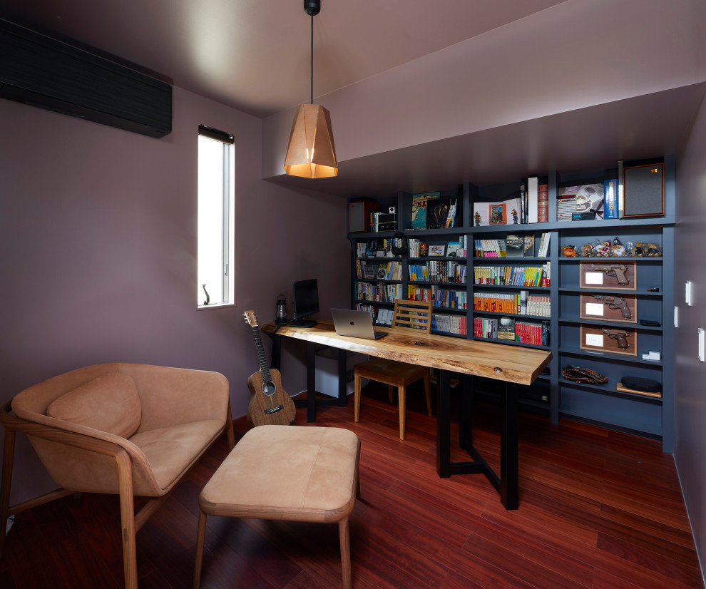 Ejemplo de despacho minimalista con paredes púrpuras, suelo de contrachapado y suelo rojo