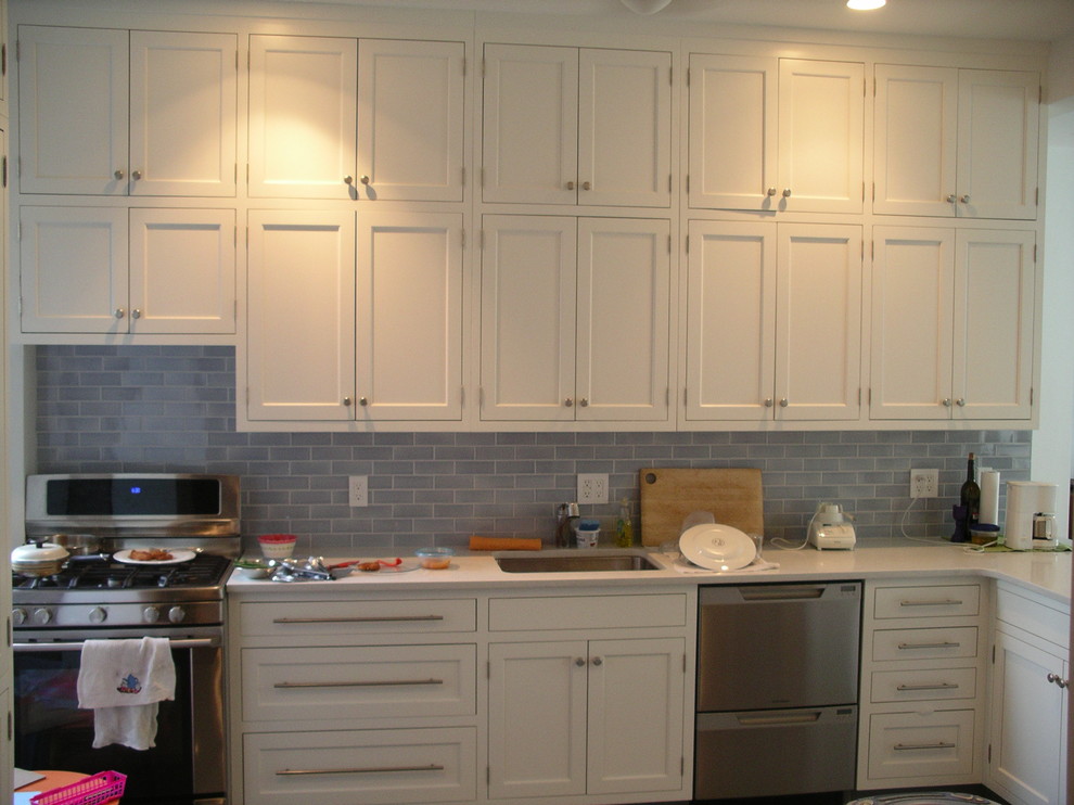 Inspiration for a mid-sized transitional u-shaped porcelain tile enclosed kitchen remodel in New York with white cabinets, stainless steel appliances, no island, an undermount sink, beaded inset cabinets, quartz countertops, blue backsplash and ceramic backsplash