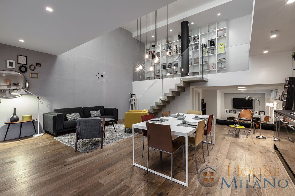 Immagine di un grande soggiorno minimal con pareti bianche, pavimento in legno massello medio e TV a parete