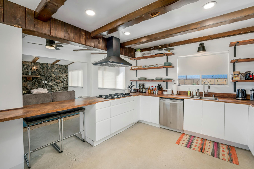 Eat-in kitchen - small modern u-shaped concrete floor, beige floor and exposed beam eat-in kitchen idea in Los Angeles with a double-bowl sink, flat-panel cabinets, white cabinets, wood countertops, stainless steel appliances, a peninsula and brown countertops