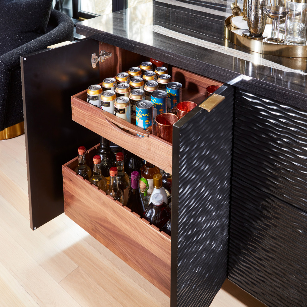 This is an example of a large modern l-shaped wet bar in New York with an undermount sink, louvered cabinets, black cabinets, glass sheet splashback, light hardwood floors, beige floor and black benchtop.