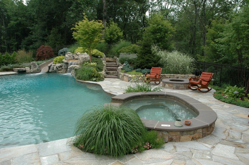This is an example of a traditional backyard custom-shaped natural pool in New York with a hot tub and natural stone pavers.