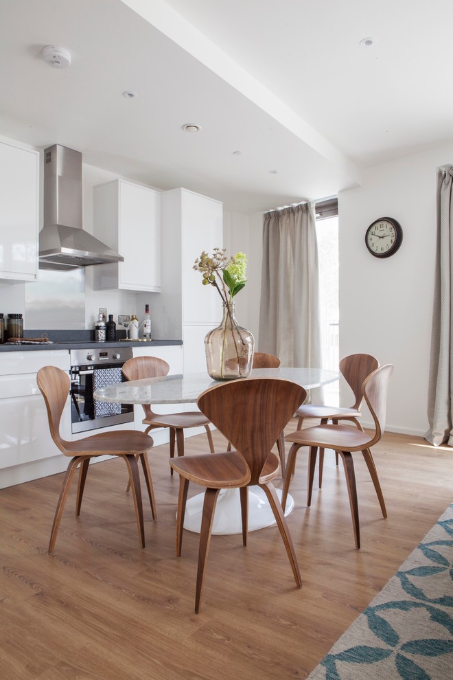 Inspiration for a contemporary kitchen/dining combo in London with white walls and medium hardwood floors.