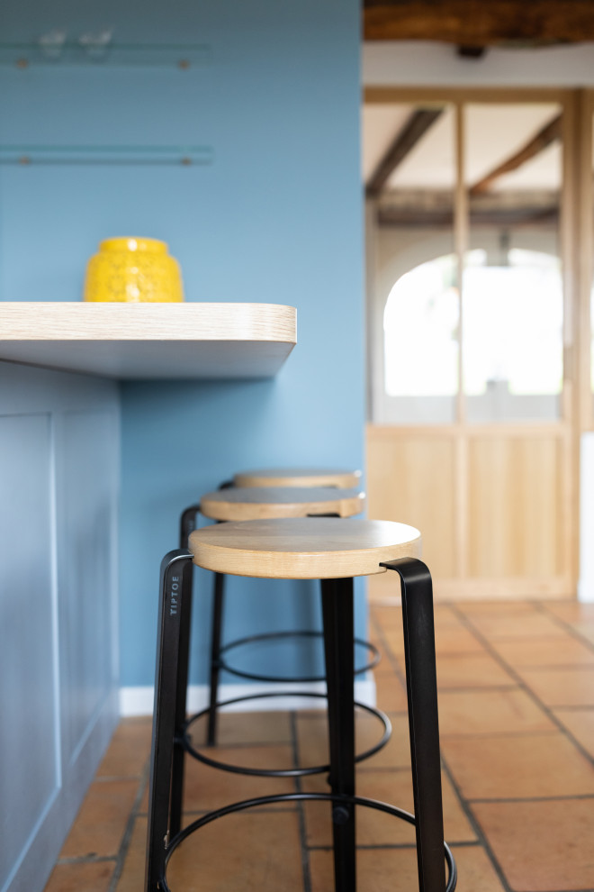 Moderne Küche mit Waschbecken, profilierten Schrankfronten, blauen Schränken, Laminat-Arbeitsplatte, Küchenrückwand in Weiß, Glasrückwand und Keramikboden in Sonstige