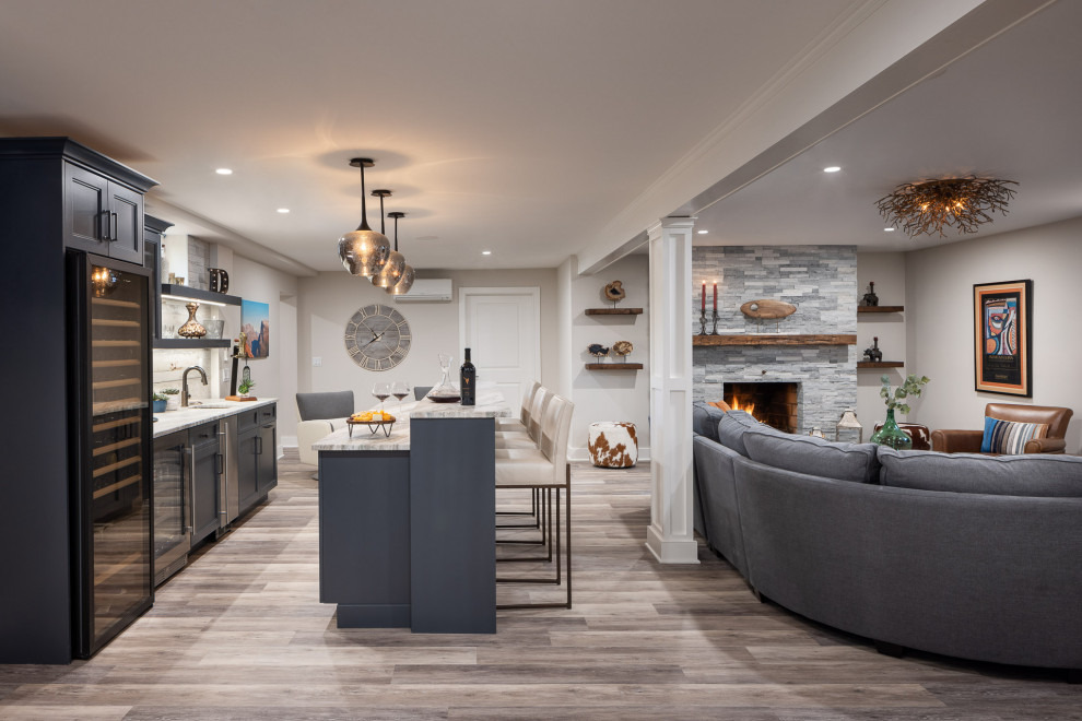 Large eclectic fully buried basement in New York with a home bar, beige walls, vinyl flooring, a standard fireplace, a stacked stone fireplace surround, grey floors, tongue and groove walls and a chimney breast.