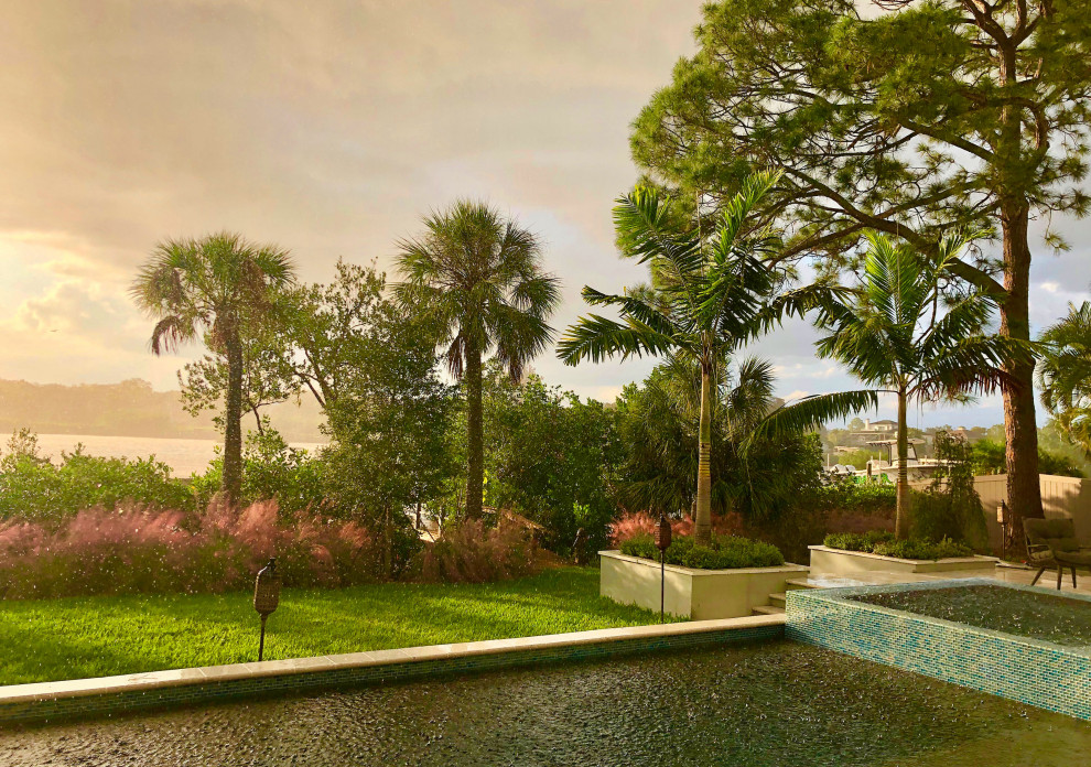 Geräumiger Garten im Frühling, hinter dem Haus mit Hochbeet, direkter Sonneneinstrahlung und Vinylzaun in Tampa