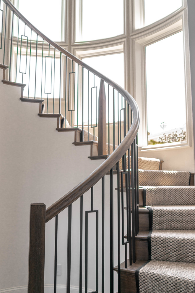 This is an example of a large contemporary wood curved staircase in San Diego with wood risers and mixed railing.
