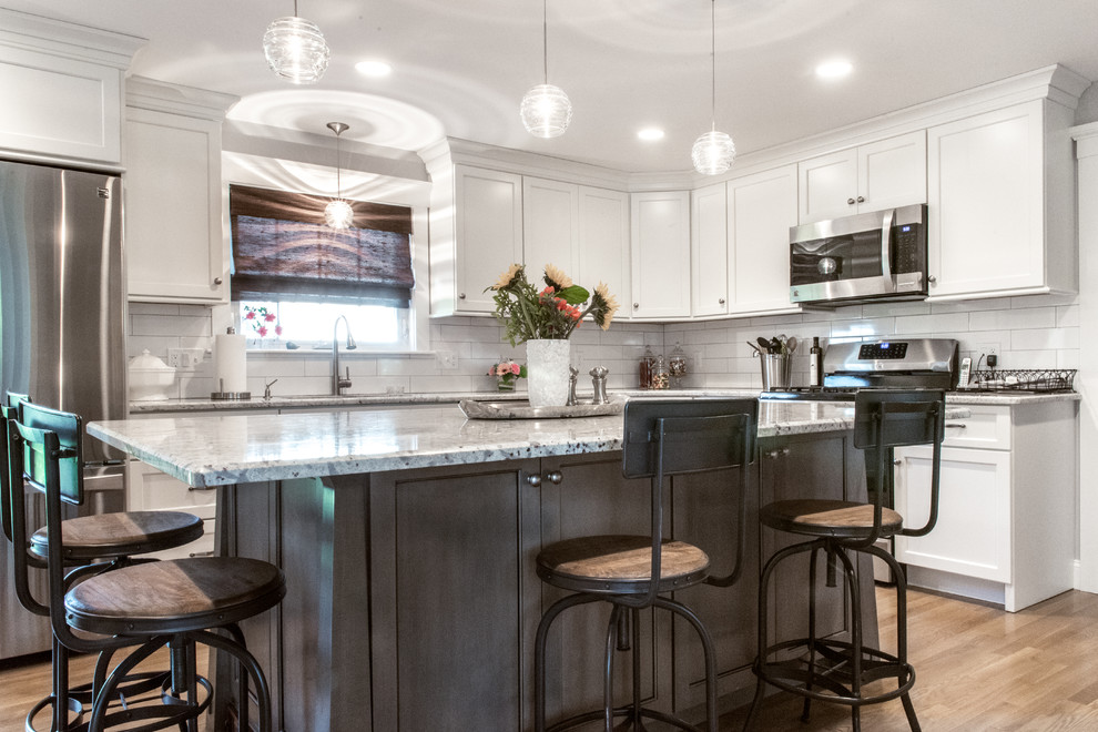 Enclosed kitchen - mid-sized transitional u-shaped medium tone wood floor enclosed kitchen idea in Boston with a double-bowl sink, recessed-panel cabinets, white cabinets, granite countertops, white backsplash, subway tile backsplash, stainless steel appliances and an island
