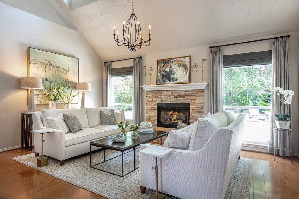 Photo of a mid-sized transitional living room in Houston with beige walls, light hardwood floors, a standard fireplace, a brick fireplace surround and brown floor.