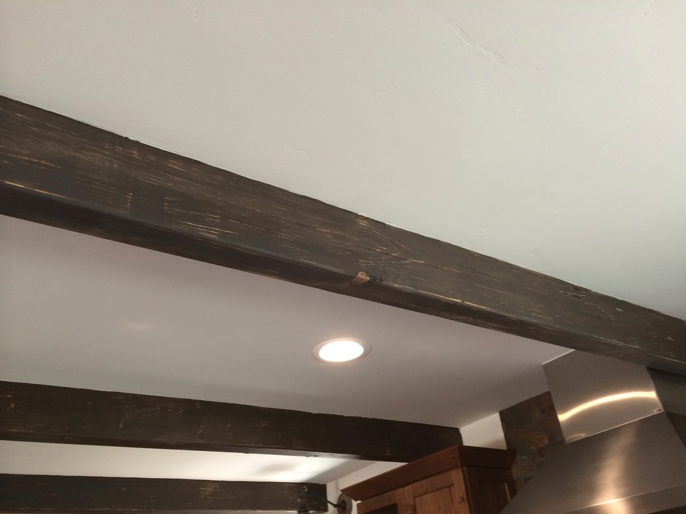 Example of a mid-sized mountain style u-shaped dark wood floor home design design in San Luis Obispo with an undermount sink, flat-panel cabinets, distressed cabinets, granite countertops, multicolored backsplash, stone tile backsplash, stainless steel appliances and an island