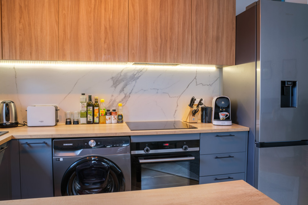 Bild på ett mellanstort funkis beige beige kök, med grå skåp, träbänkskiva, vitt stänkskydd, stänkskydd i marmor, mellanmörkt trägolv, en köksö och beiget golv