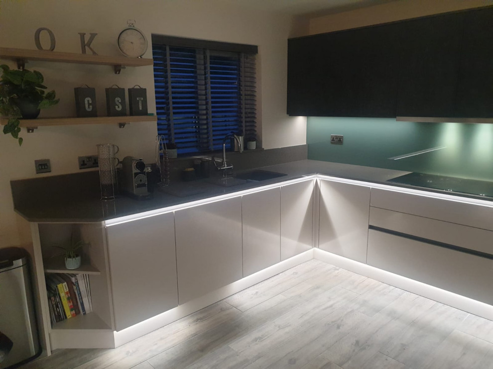 This is an example of a medium sized contemporary grey and black u-shaped open plan kitchen in Other with quartz worktops, green splashback, glass sheet splashback, stainless steel appliances, vinyl flooring, an island, grey floors, grey worktops and feature lighting.