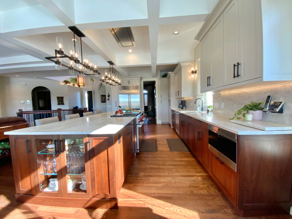 Inspiration for a large transitional single-wall dark wood floor, brown floor and coffered ceiling eat-in kitchen remodel in Calgary with an undermount sink, shaker cabinets, white cabinets, quartzite countertops, white backsplash, stainless steel appliances, an island, white countertops and stone slab backsplash