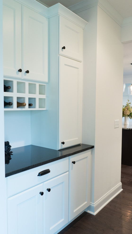 Inspiration for a mid-sized transitional l-shaped dark wood floor open concept kitchen remodel with an undermount sink, shaker cabinets, white cabinets, granite countertops, gray backsplash, stainless steel appliances and an island