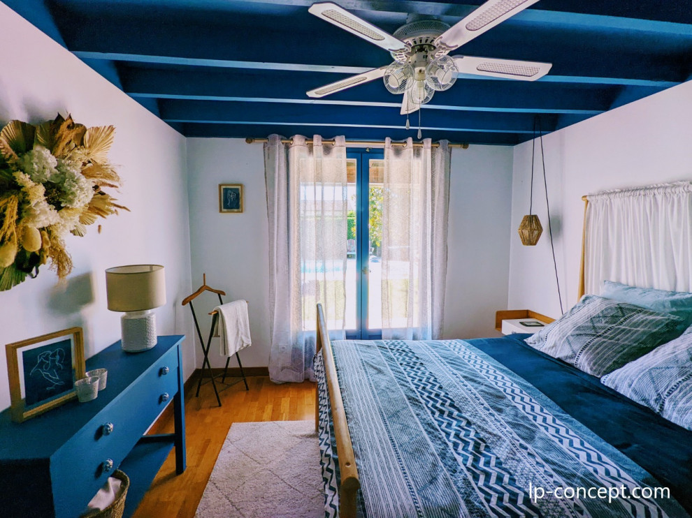 Modelo de dormitorio blanco y madera marinero de tamaño medio con paredes blancas, suelo de madera clara y vigas vistas