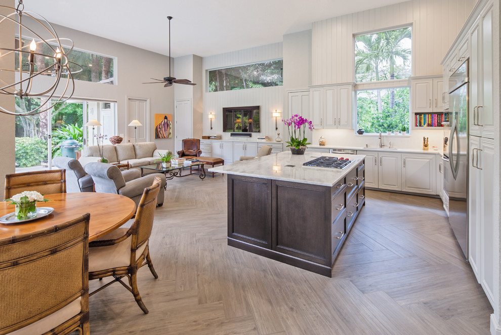 Photo of a large transitional l-shaped open plan kitchen in Miami with an undermount sink, raised-panel cabinets, white cabinets, quartzite benchtops, white splashback, stone slab splashback, stainless steel appliances, porcelain floors and with island.