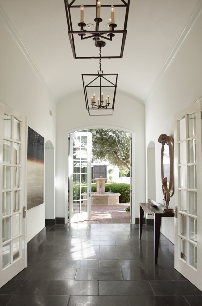 Large transitional entryway in Phoenix with white walls, limestone floors, a single front door, a black front door and black floor.
