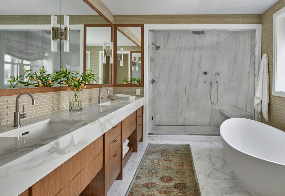 Mid-sized transitional master bathroom in Chicago with flat-panel cabinets, medium wood cabinets, a freestanding tub, a corner shower, beige tile, glass sheet wall, beige walls, marble floors, an undermount sink, marble benchtops, white floor, a hinged shower door, white benchtops, a shower seat, a double vanity and a built-in vanity.